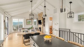 A spacious kitchen with a large island, a stone fireplace, and a balcony with a view. - Vineyard Views w/ Pool & Game Room Near Trails, Wineries Beginnings Ranch & Vineyard by Avantstay (Paso Robles)