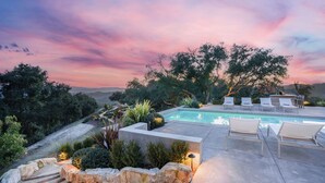 A pool with lounge chairs, surrounded by landscaped garden beds and trees, under a twilight sky. - Vineyard Views w/ Pool & Game Room Near Trails, Wineries Beginnings Ranch & Vineyard by Avantstay (Paso Robles)