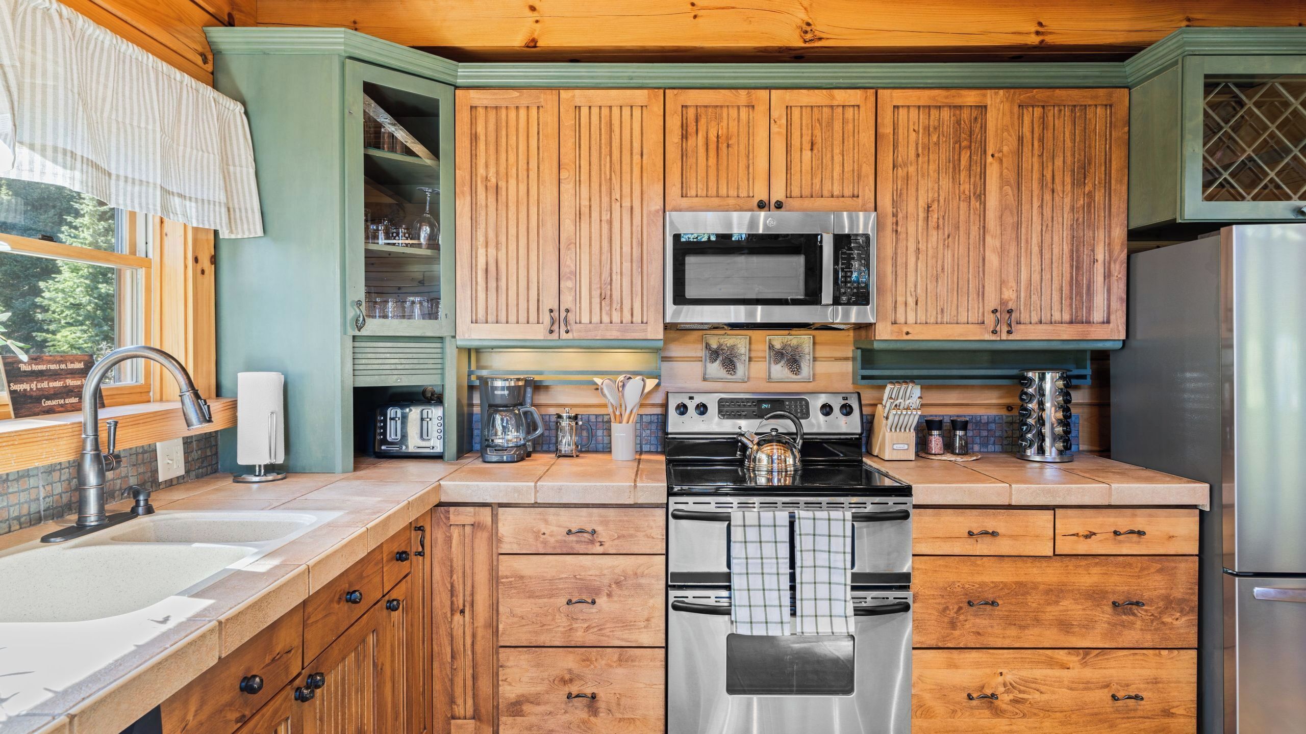 A kitchen with wooden cabinets, a stainless steel stove, a microwave, and a refrigerator.