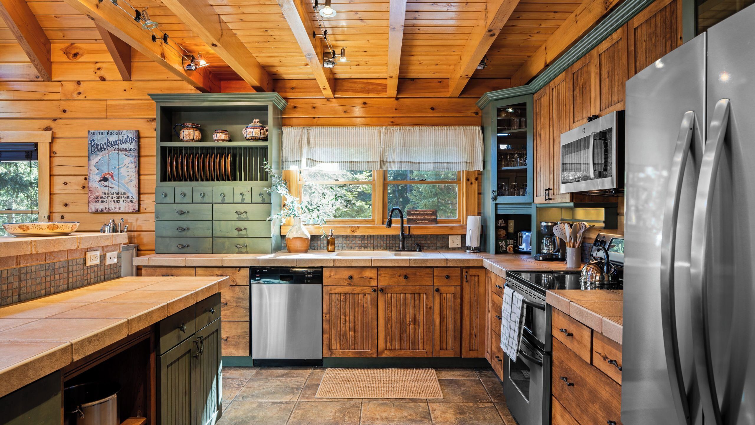 Eine Küchenzeile im Chalet-Stil mit Geschirrspüler, Herd und einem großen Kühlschrank.