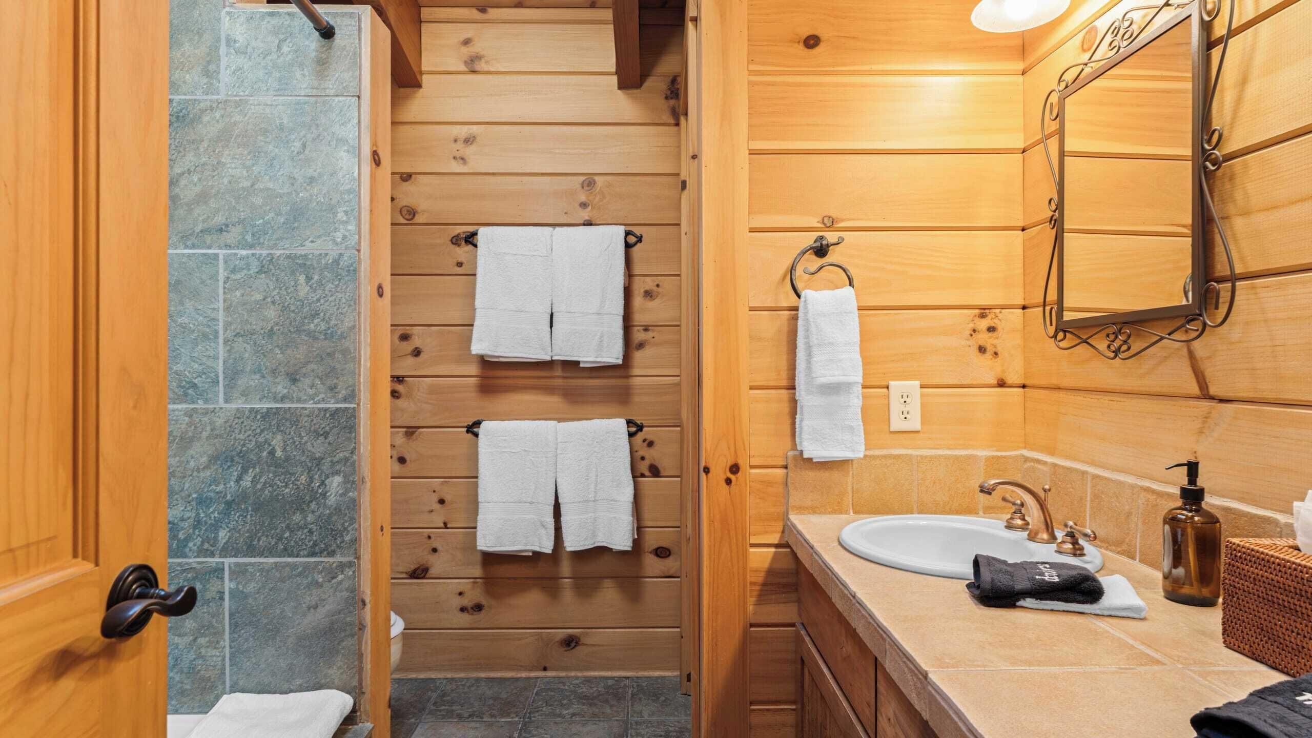 Un baño de madera con lavamanos, espejo y toallero.