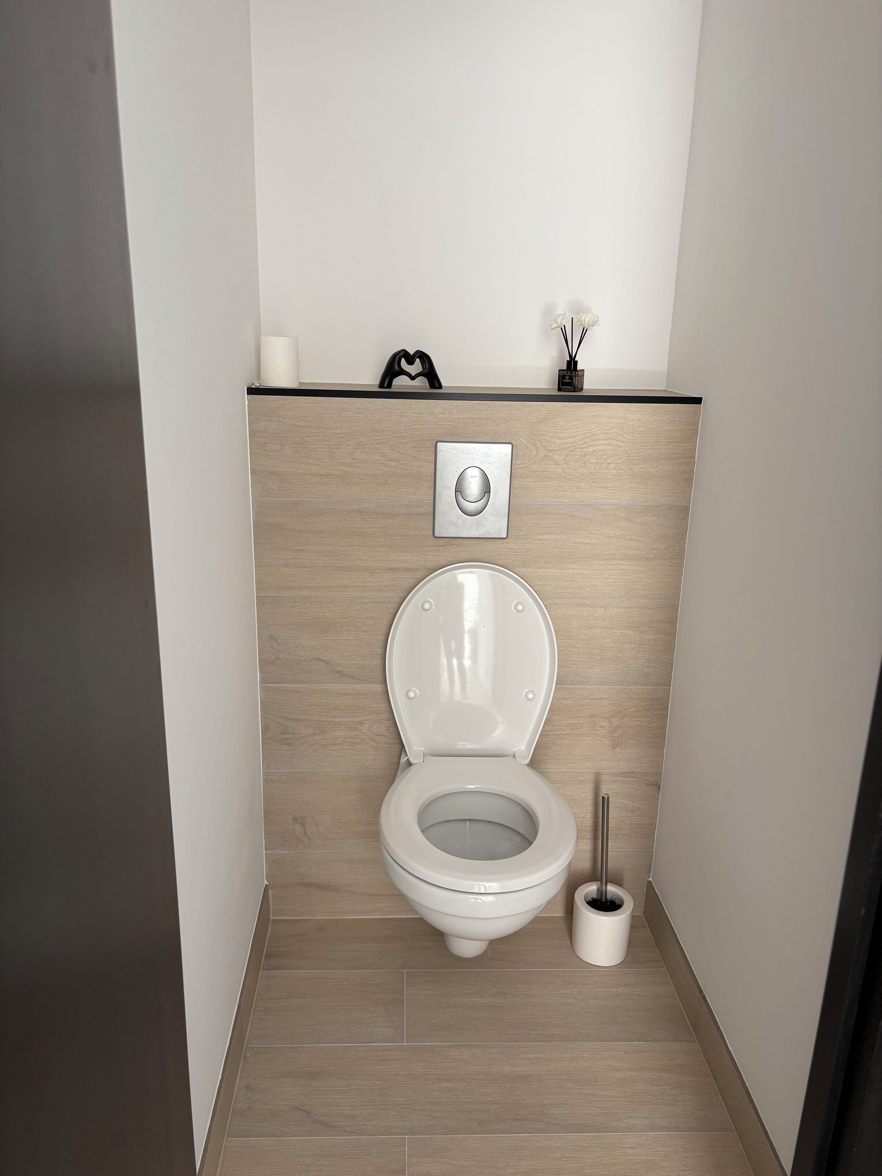 Uma casa de banho moderna com sanita, bidé e suporte de papel higiénico na parede.