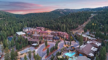 A resort with multiple buildings, a swimming pool, and a mountainous backdrop.