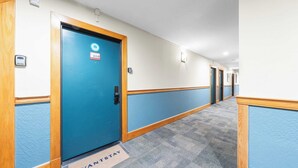 A hotel hallway with a blue door marked 208, carpeted floors, and wooden trim. - Cozy Northstar Village Escape w/ Forest Views & Easy Lift Access Alpineglow Vista by Avantstay (Truckee)