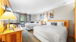 A hotel room with two beds, a wooden desk with a lamp, a view of the outdoors, and artwork on the wall. - Cozy Northstar Village Escape w/ Forest Views & Easy Lift Access Alpineglow Vista by Avantstay (Truckee)