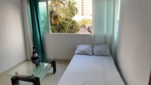 A small, single-bed room with a window, a table, and a chair. - Em3-1g 1 Bedroom Apartment in Residential Area air Conditioning and Wifi (Cartagena)