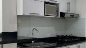 A kitchen with white cabinets, a black countertop, a microwave, and a trash bin. - Em3-1g 1 Bedroom Apartment in Residential Area air Conditioning and Wifi (Cartagena)
