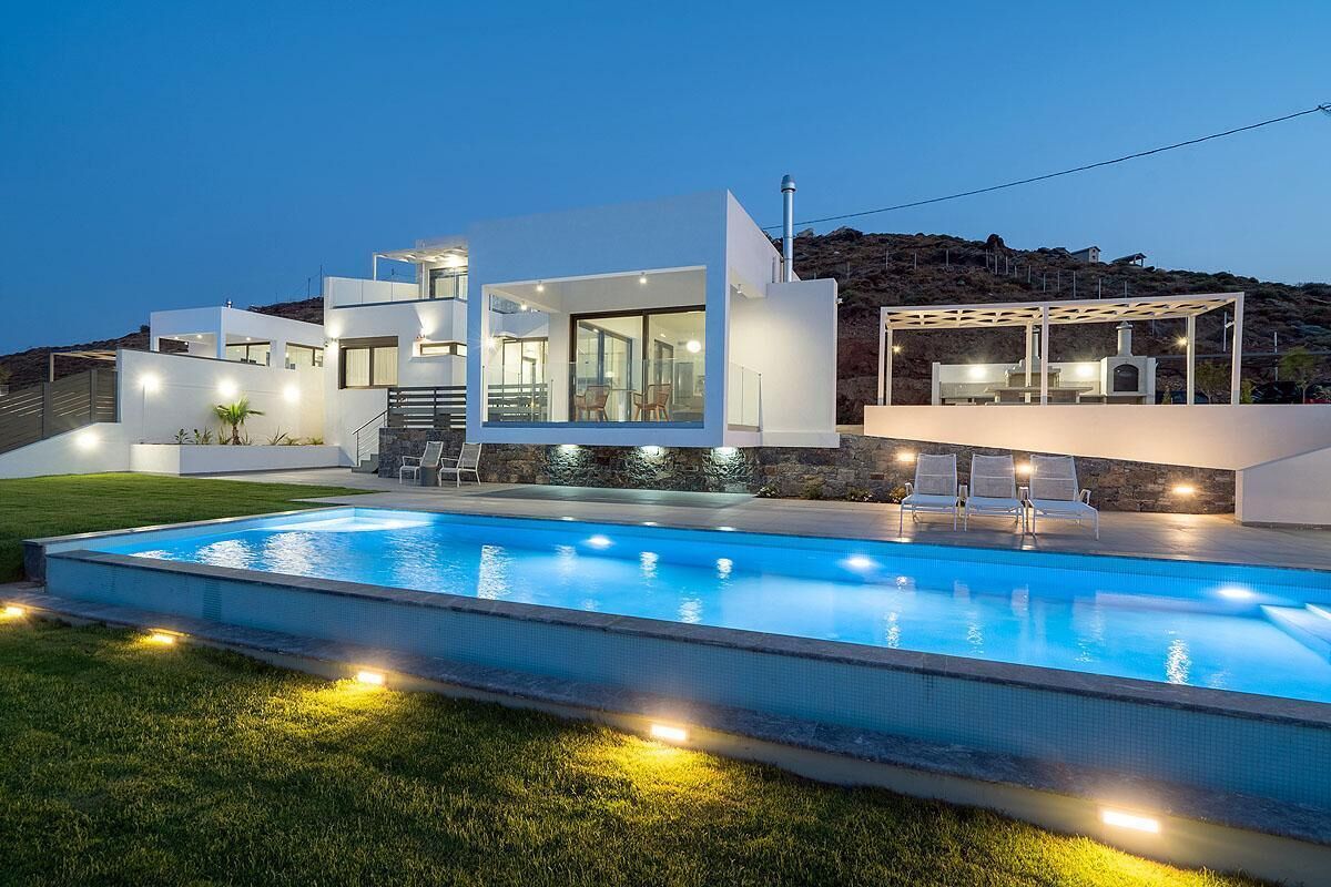 Ein modernes Haus mit Pool, Sitzgelegenheiten im Freien und einer Steinmauer.
