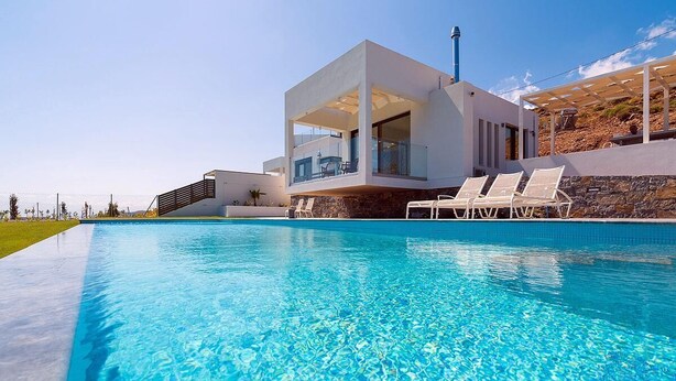 Une maison moderne dotée d’une piscine, d’une façade blanche et d’un mur en pierre.