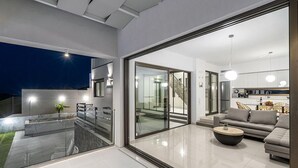 Un salon moderne avec un mur en verre, un escalier et un coin cuisine.