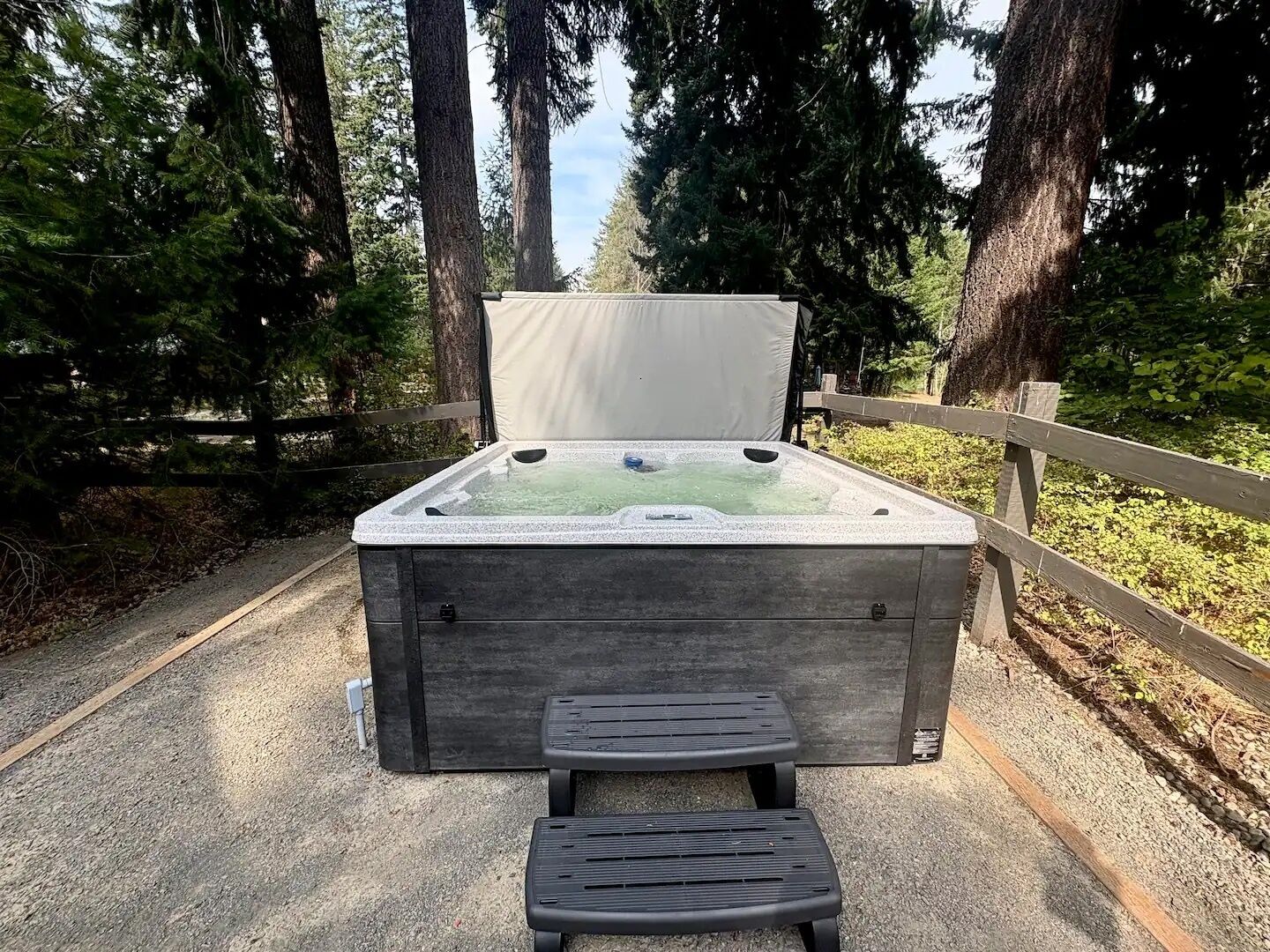 A hot tub with a bench in a forested area.