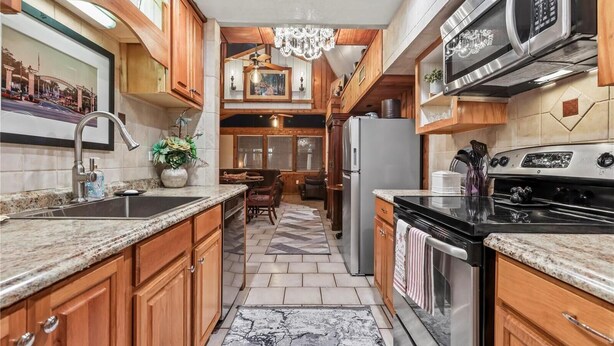 A kitchen with wooden cabinets, granite countertops, stainless steel appliances, and a chandelier. - 3-bedroom cabin in gorgeous Clermont with AC (Clermont)