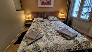 Et hotelværelse med en stor seng, to sengeborde, en sengegavl, et vindue med udsigt og et skilt på væggen med teksten 'WOW!'.