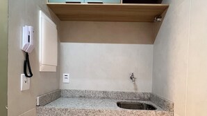 Una cucina compatta con un piano di lavoro in granito, un lavello e mobili verdi.