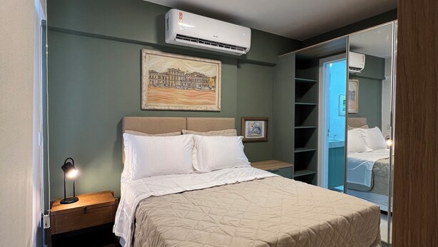 Camera da letto con un letto, comodino, aria condizionata e uno specchio.