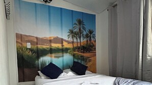 Une chambre à coucher avec un lit, une peinture murale, un luminaire au plafond et une fenêtre avec des rideaux.