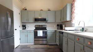 A kitchen with light blue cabinets, stainless steel appliances, and a wooden floor. - Bright Arvada Townhome with Backyard, Walkable to Old Town Arvada (Arvada)