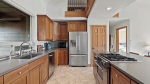 A modern kitchen with wooden cabinets, stainless steel appliances, and a large island.