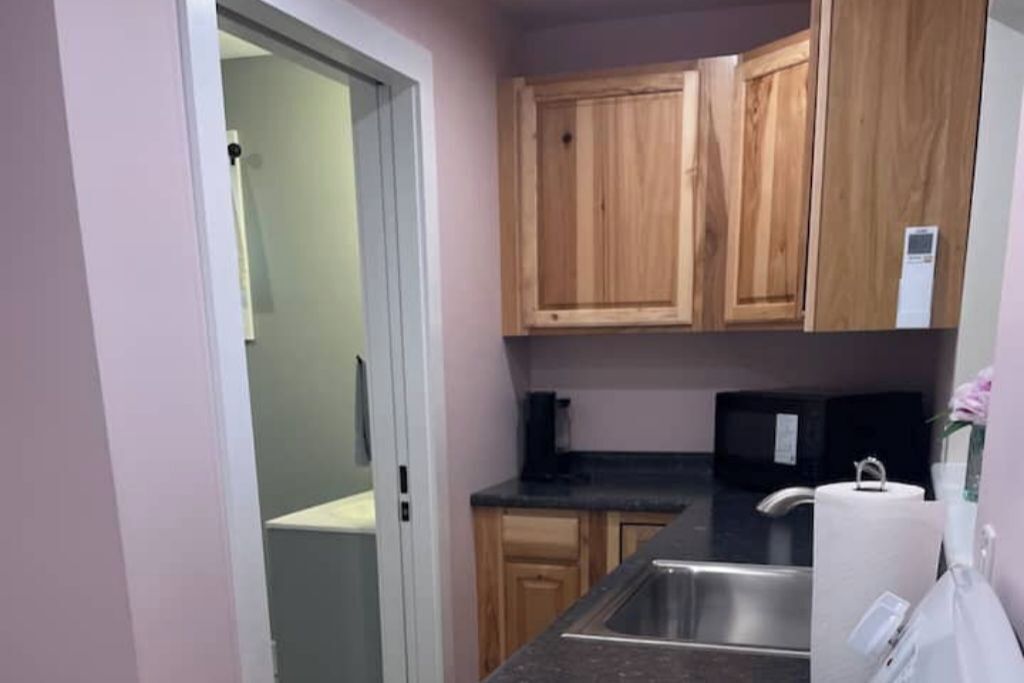 A kitchen with wooden cabinets, a stainless steel sink, and a black countertop.