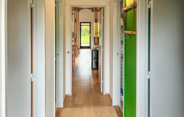 Un couloir avec un plancher en bois, des murs blancs et une porte verte sur le côté droit.