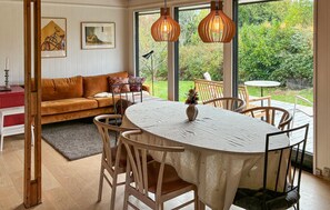Un coin repas avec une table ronde, des chaises et une vue sur le jardin grâce à de grandes fenêtres.