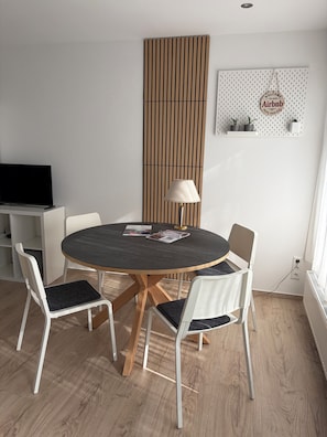 Ein moderner Essbereich mit einem runden Tisch, vier weißen Stühlen, einer Lampe und einem an der Wand befestigten Schild.