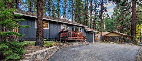 A cabin with a stone retaining wall, a wooden deck, and a garage.