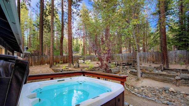A hot tub in a forested backyard with a wooden deck and a stone pathway. - Private Woods - Heavenly California Lodge (South Lake Tahoe)
