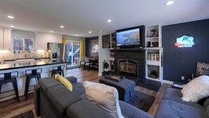 A modern living room with a fireplace, a kitchen with a large island, and a dining area. - Private Woods - Heavenly California Lodge (South Lake Tahoe)