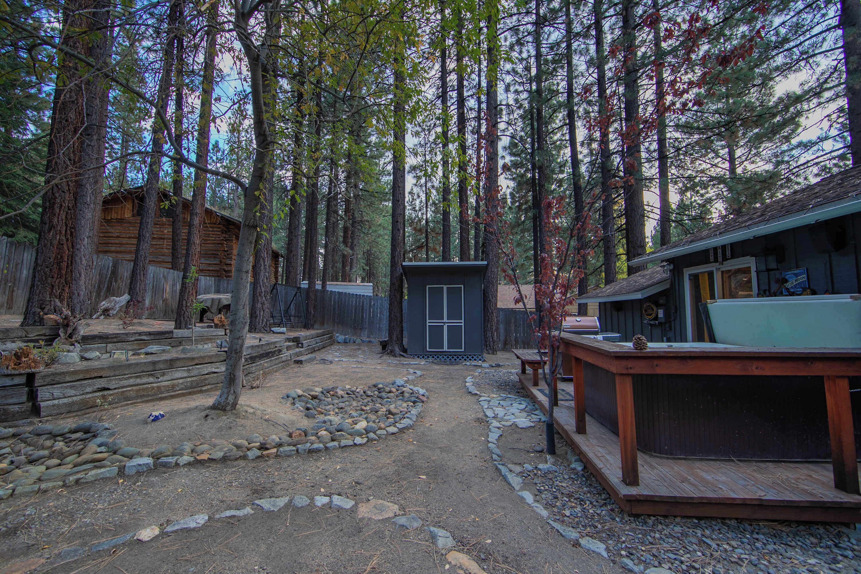 A rustic cabin with a wooden deck, a small shed, and a stone pathway.