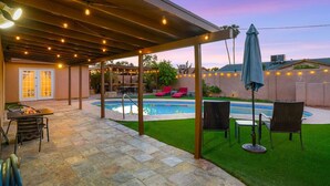 Ein Garten mit Pool, Sitzgelegenheiten im Freien und Lichterketten.