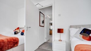 Ein Hotelzimmer mit zwei Betten, einem Nachttisch, einem Fernseher und einer Tür zu einem Badezimmer.