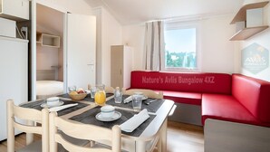 A dining area with a table set for two, a red sofa, and a view of the outdoors.