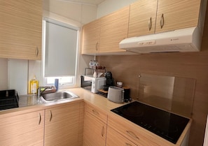 A compact kitchen with wooden cabinets, a built-in stove, a sink, and a window providing natural light.