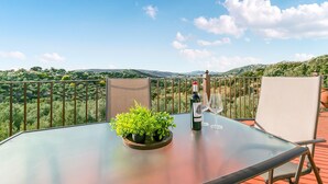 Et bord med en vinflaske, et glas og en potteplante på en balkon med et smukt vue.