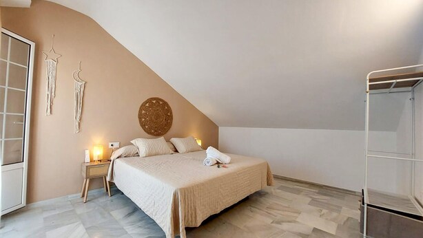 Une chambre à coucher comprenant un lit, des tables de chevet, un élément décoratif mural et une armoire.
