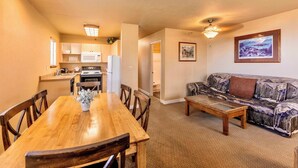 A compact living space with a wooden dining table, chairs, a sofa, and a kitchen area with appliances. - Galaxy Way Close to Stagecoach Chair! (Stateline)