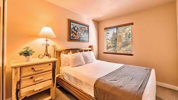 A neatly arranged bedroom with a bed, bedside table, lamp, and a window with blinds.
