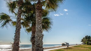 Una playa con palmeras, un camino y una escultura de elefante.