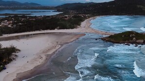 A coastal landscape with a beach, ocean waves, and distant hills. - Pousada da Praia Ferrugem (Garopaba)