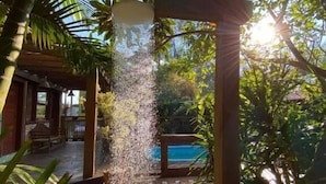 A covered outdoor area with a water feature, brick flooring, and surrounding greenery. - Pousada da Praia Ferrugem (Garopaba)