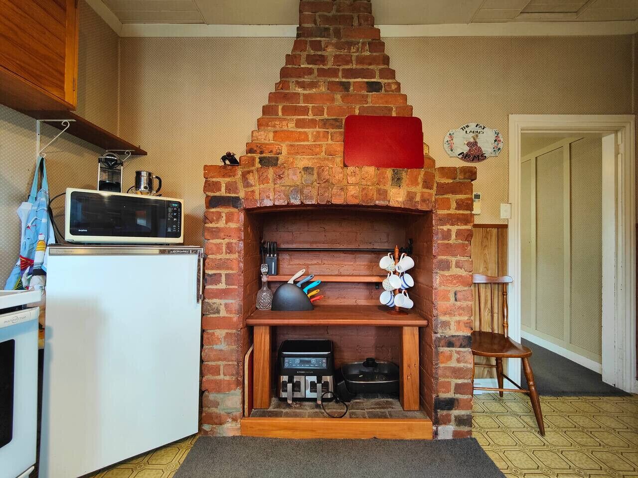 A compact kitchen with a brick fireplace, a microwave, a toaster, and a small refrigerator.