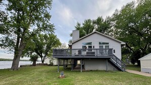 A two-story house with a balcony, a covered porch, and a view of a lake.