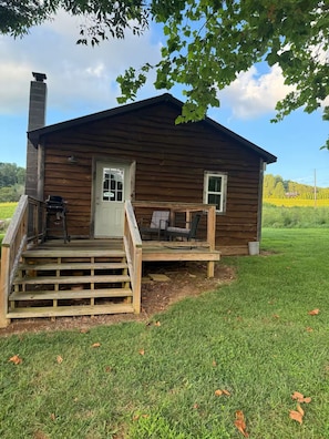 Eine Holzhütte mit Veranda, Schornstein und kleiner Terrassenfläche.