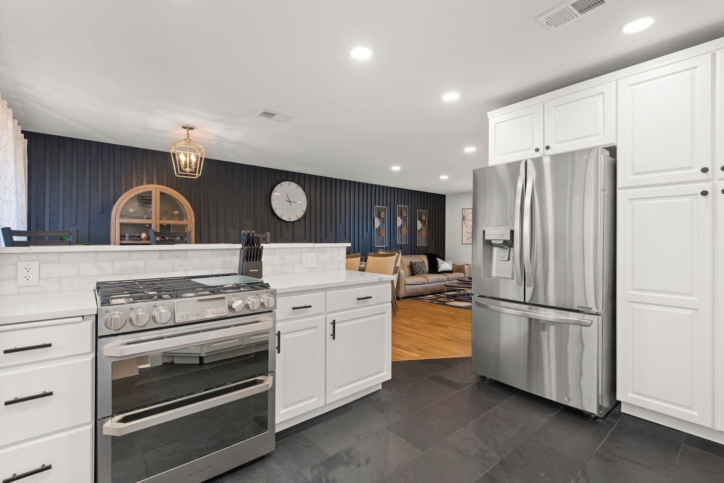 Una cocina moderna con armarios blancos, un refrigerador de acero inoxidable, un horno empotrado y una estufa a gas.