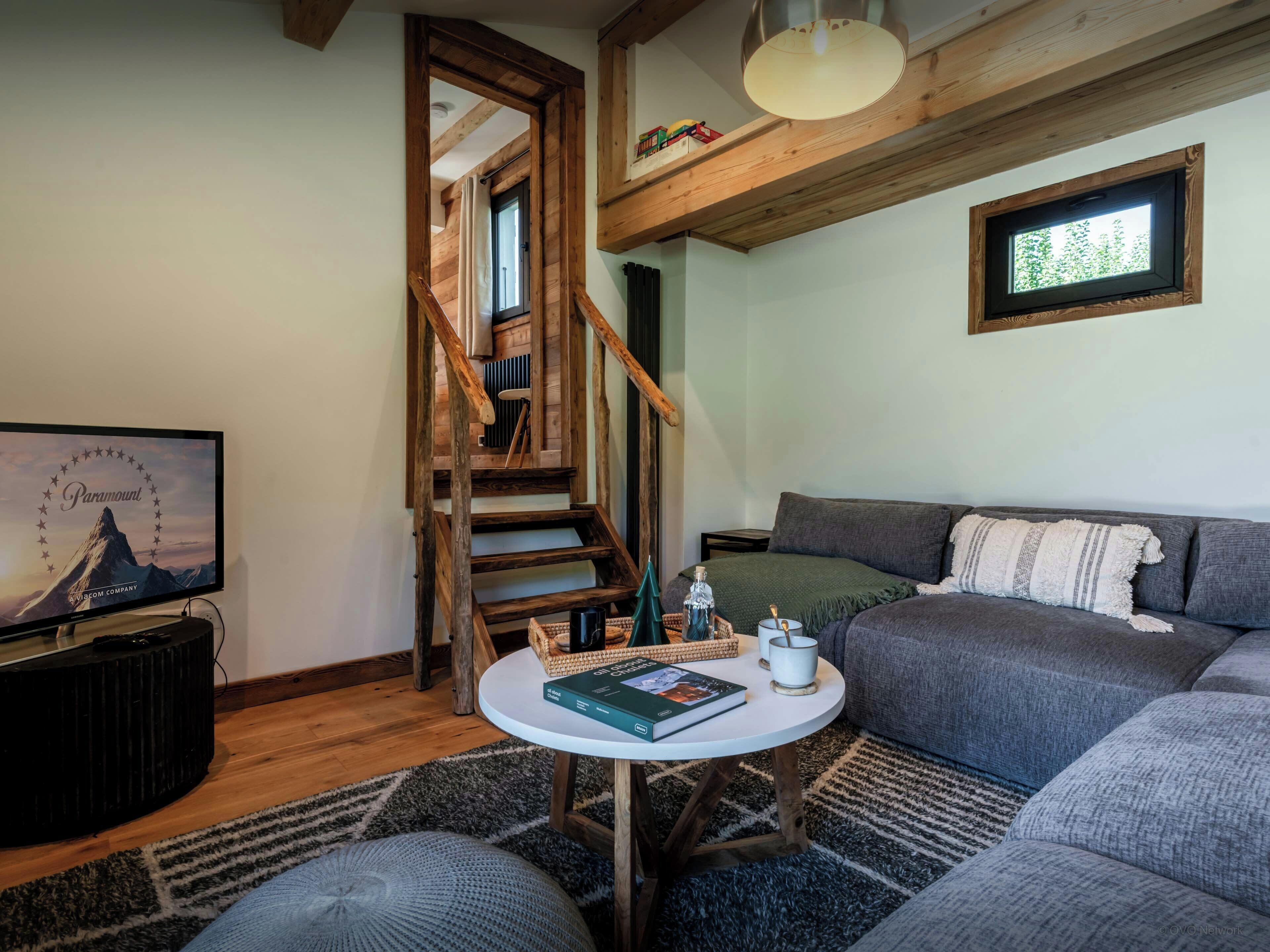 Una sala de estar acogedora con una escalera, un televisor, un sofá y una mesa de centro.