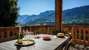 A wooden deck with a table set for a meal, overlooking a mountainous landscape.