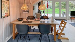 Un comedor con una mesa de madera, dos sillas negras y una lámpara colgante.