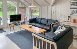 En moderne stue med sofa, sofabord og fjernsyn.