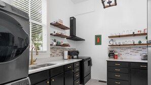 Eine moderne Küche mit schwarzen Schränken, einem eingebauten Backofen und einer Kaffeemaschine.